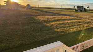 A large open field with a house and a small structure in the distance. - The Pink House - beautiful beach stay! (Galveston)