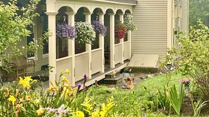 A house with a porch adorned with hanging flower baskets.