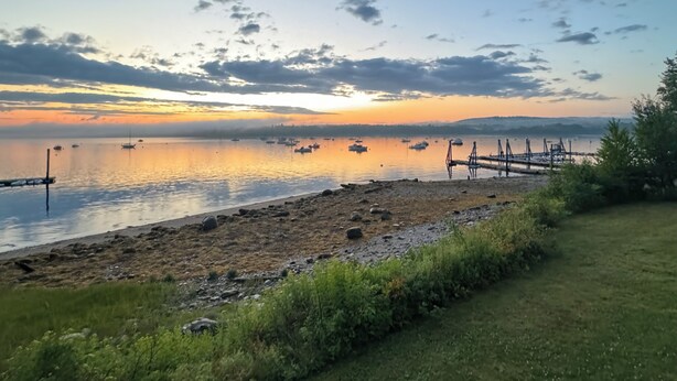 A serene lakeside view with boats, a dock, and a grassy area.