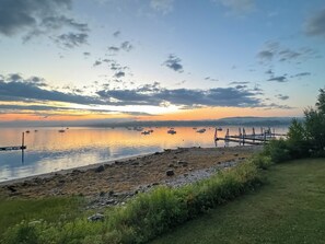 A serene lakeside view with boats, a dock, and a grassy area.