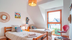 A bedroom with two beds, a large window, and a view of the outside. - Ty Kéréré - Maison 3★ - Calme, Grand Jardin Arboré, 500m plage (Locmariaquer)