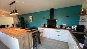 Een moderne keuken met een houten kookeiland, witte kastjes en een wand in teal blauw.