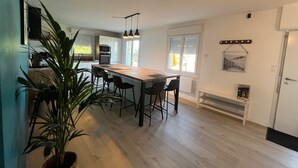 Een moderne keuken met een houten kookeiland, barstoelen en een grote potplant.