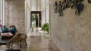 A hallway with a stone wall, a wooden floor, and a seating area with chairs and a table.