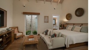 A spacious room with a large bed, a sofa, a wooden coffee table, and a television.
