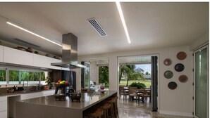 A modern kitchen with a large island, bar stools, and a view of the outdoors.