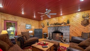 L’intérieur d’un chalet confortable, avec des murs en rondins de bois, une cheminée en pierre, des meubles en cuir et des têtes d’animaux décoratives accrochées aux murs.