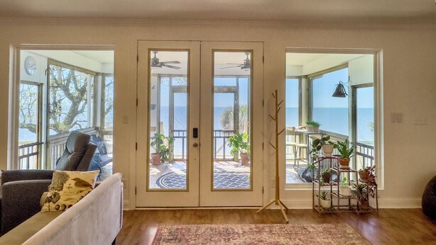A spacious living room with a large sliding glass door leading to a balcony with a view of the ocean.