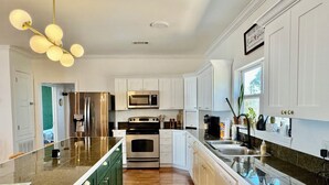 A modern kitchen with white cabinets, stainless steel appliances, and a granite countertop.