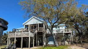 A two-story wooden house with a balcony and a tree in front.