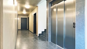 En modern hall med ett marmorgolv, en trappa och en väggmonterad hiss.