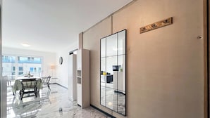Ett modernt hotellrum med en stor spegel, en matplats med bord och stolar samt utsikt över balkongen.