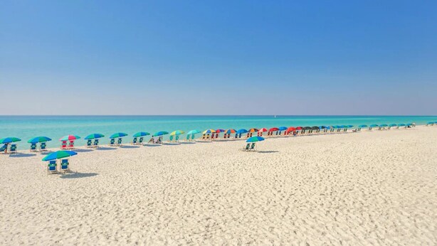 A beach with rows of beach chairs and umbrellas under a clear sky. - Harbor Views,  Fully Renovated, Free Beach Service, Pools, Pickleball, Free golf (Destin)
