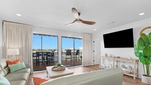 A modern living room with a sofa, a coffee table, and a television mounted on the wall. - Harbor Views,  Fully Renovated, Free Beach Service, Pools, Pickleball, Free golf (Destin)