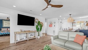 A modern living room with a sofa, a coffee table, and a TV mounted on the wall. - Harbor Views,  Fully Renovated, Free Beach Service, Pools, Pickleball, Free golf (Destin)