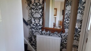 A staircase with a white radiator, a mirror, and patterned wallpaper. - House-sleeps 5-parking-bbq-garden-patio (Chesterfield)