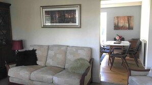 A living room with a sofa, a dining table with chairs, and two paintings on the walls. - House-sleeps 5-parking-bbq-garden-patio (Chesterfield)