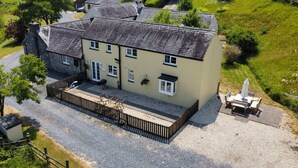 A two-story house with a gravel driveway and a fenced patio area. - Meadow Sweet, Meadowsweet Cottage Jacuzzi Edition (Saundersfoot)