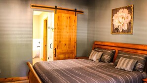A bedroom with a wooden bed, a sliding door, and a painting of a flower on the wall. - 3 Amigos-golf, canyon, RV garage (Williams)