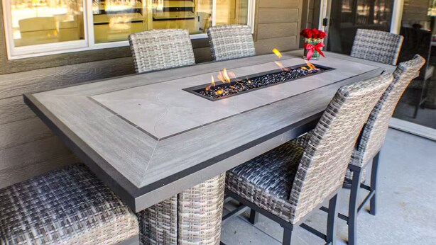 A rectangular outdoor dining table with a built-in fire feature, surrounded by wicker chairs. - 3 Amigos-golf, canyon, RV garage (Williams)