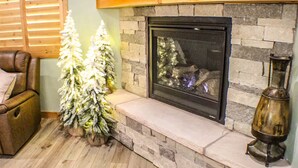 A fireplace with a stone surround, two artificial Christmas trees, and a leather armchair. - 3 Amigos-golf, canyon, RV garage (Williams)