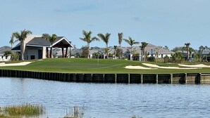 A golf course with a water body in the foreground, a pavilion, and residential buildings in the background. - 2 bed 2 bath GOLF condo in Webbs Reserve (Punta Gorda)