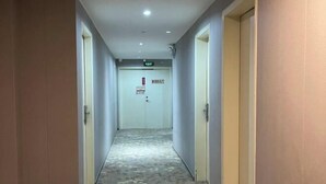 Un pasillo con alfombra estampada que lleva a una puerta con un cartel.