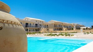 Een resort met een zwembad, strandvillas en een grote decoratieve vaas.