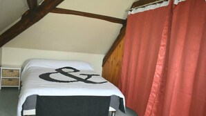 Ein Schlafzimmer mit einem Bett, einem roten Vorhang und einem weißen Nachttisch mit einem Korb.