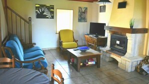 Ein Wohnzimmer mit Kamin, Fernseher und einem gelben Sessel.