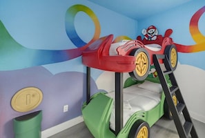 Uma cama beliche com decoração temática do Mario, uma escada e uma lixeira.