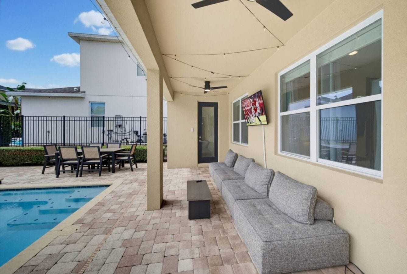A covered patio with a pool, outdoor furniture, and a ceiling fan.