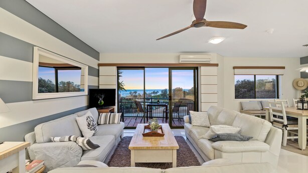 A modern living room with a sofa, coffee table, and a balcony with a view.