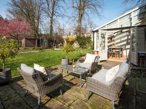 A patio with wicker furniture, a glass table, and a potted plant. - The Old Coach House (Alnwick)