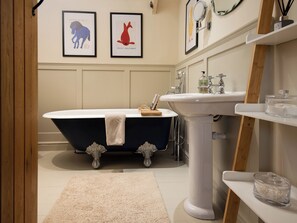 A bathroom with a freestanding bathtub, a pedestal sink, and framed artwork on the wall. - The Old Coach House (Alnwick)