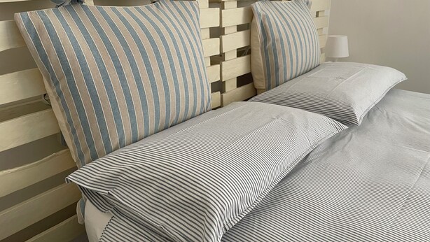 A bed with striped bedding and a headboard with a knot design. - Apartment for 4 people Appio district (Roma)