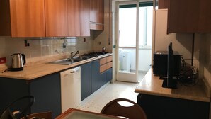 A kitchen with wooden cabinets, a dishwasher, a stove, and a sink. - Apartment for 4 people Appio district (Roma)