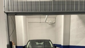 A car parked in a garage with white walls and blue stripes. - Apartment for 4 people Appio district (Roma)
