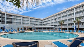 A hotel with a large pool surrounded by blue lounge chairs and a multi-story building with balconies. - New listing! Completely remodeled Villa. Beachfront with view of main pool. (Hilton Head Island)