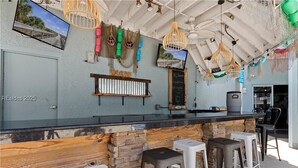 A bar area with a stone counter, bar stools, and hanging decorative lights. - New listing! Completely remodeled Villa. Beachfront with view of main pool. (Hilton Head Island)
