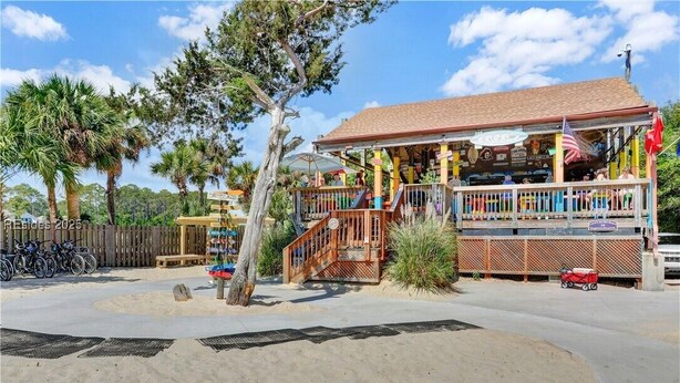 A beachside building with a covered porch, a small staircase, and a sandy area with a palm tree. - New listing! Completely remodeled Villa. Beachfront with view of main pool. (Hilton Head Island)