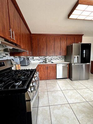 A modern kitchen with wooden cabinets, stainless steel appliances, and a tiled floor. - Stardust Skies Retreat (Albuquerque)