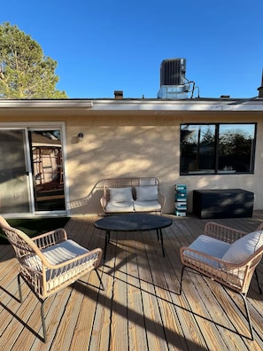 A covered outdoor patio with wicker furniture, a table, and a large window.