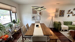 Un espace repas comprenant une table en bois, des chaises, un tapis à motifs et un luminaire suspendu.
