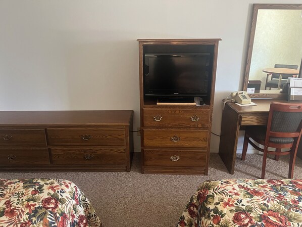 A room with a wooden dresser, a desk with a telephone, and a chair. - Aurora Inn (Aurora)