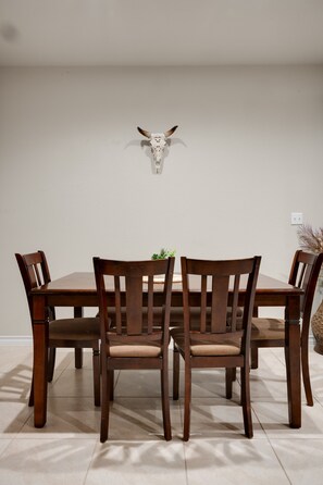 Une table à manger avec quatre chaises, une décoration murale représentant une tête de taureau et une petite plante posée sur la table.