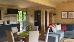 A cozy cabin interior with a dining area, a sofa, and a kitchen. - Primrose (Chard)