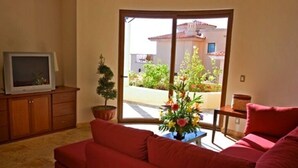 Ein Wohnzimmer mit einem roten Sofa, einem Fernseher auf einem Holzschrank und einer Topfpflanze.