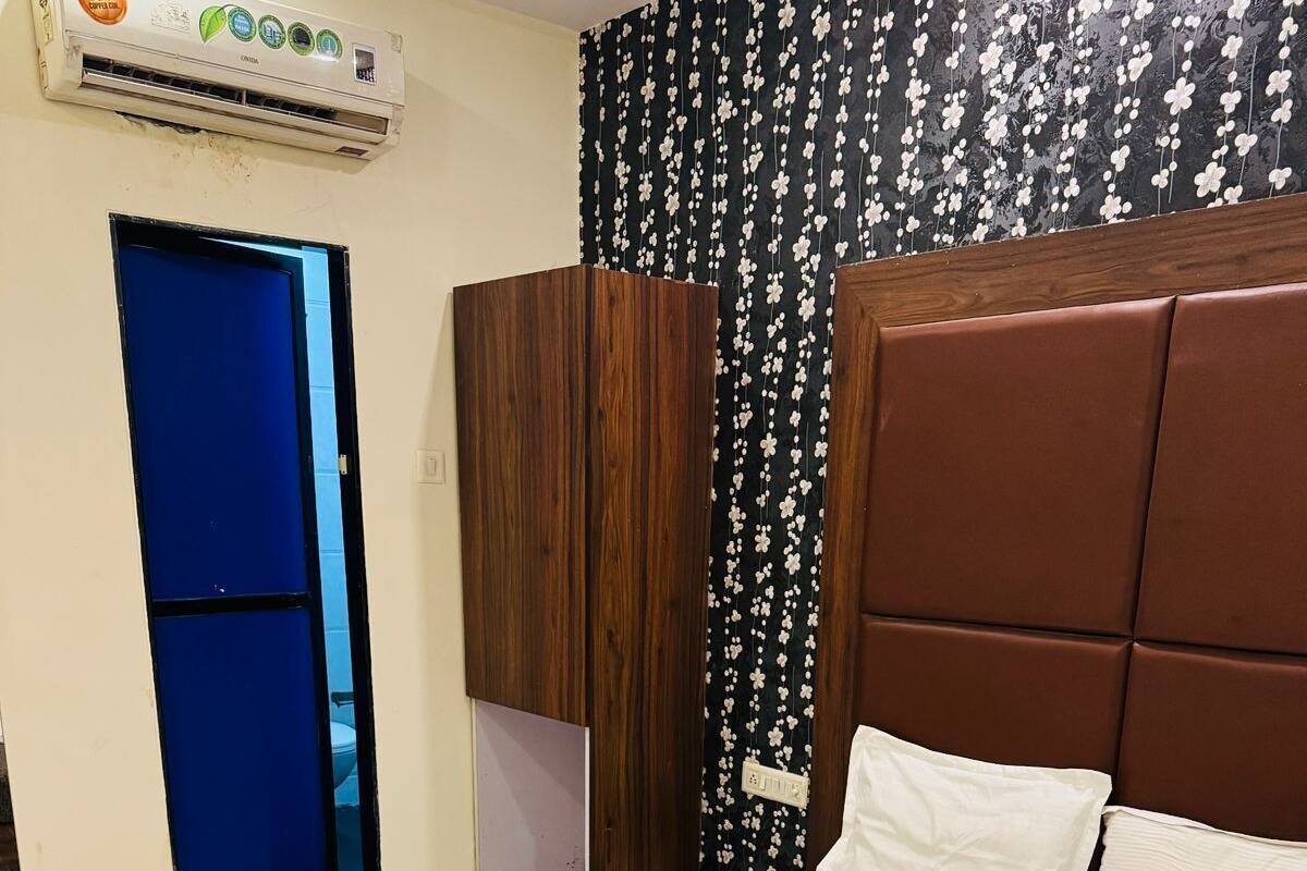 Una habitación de hotel con cama, armario, puerta azul y papel tapiz floral.