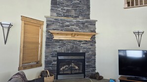 Una sala de estar con chimenea de piedra, televisor y escalera de madera.